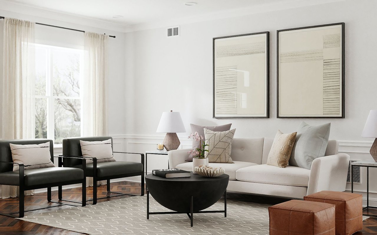 A clean and modern living room with a white sofa, two black chairs, a round coffee table, and large abstract art.